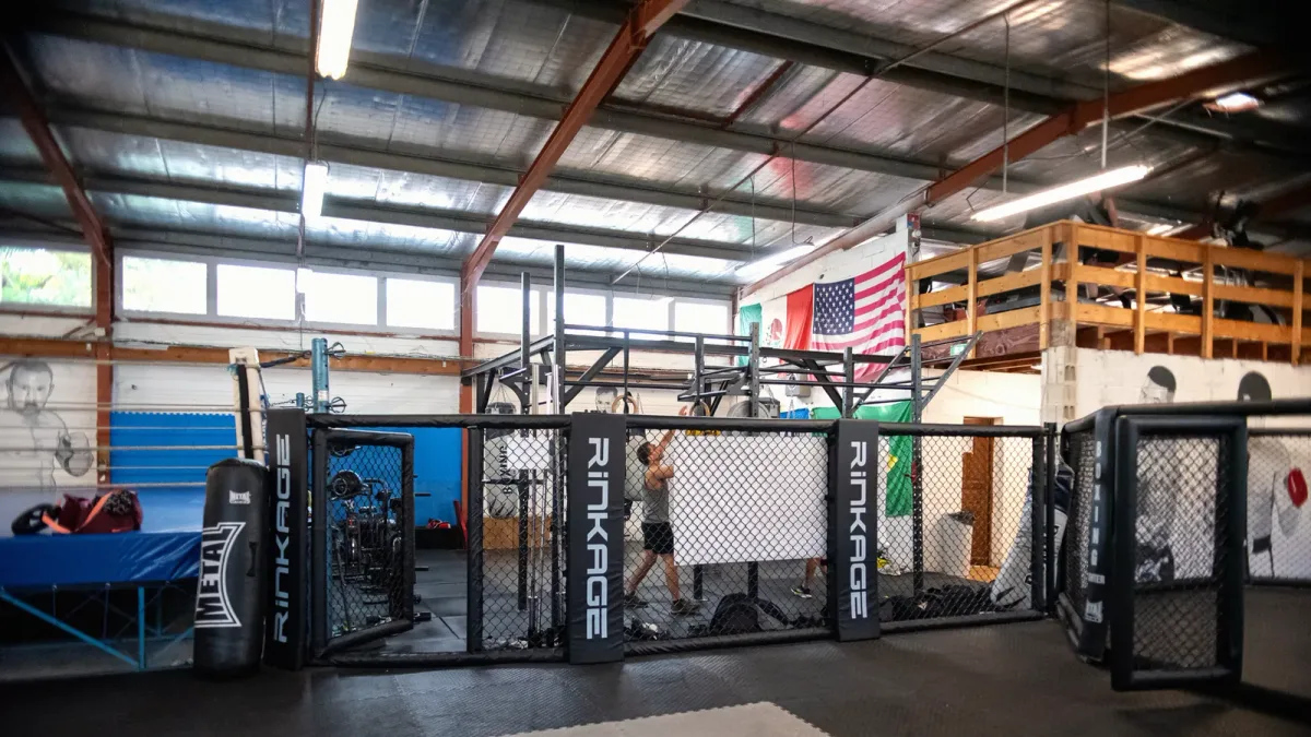 Le plateau couvert du Boxing Center Ramonville : l’octogone de 7 mètres, le ring de boxe et les tatamis sous la charpente.