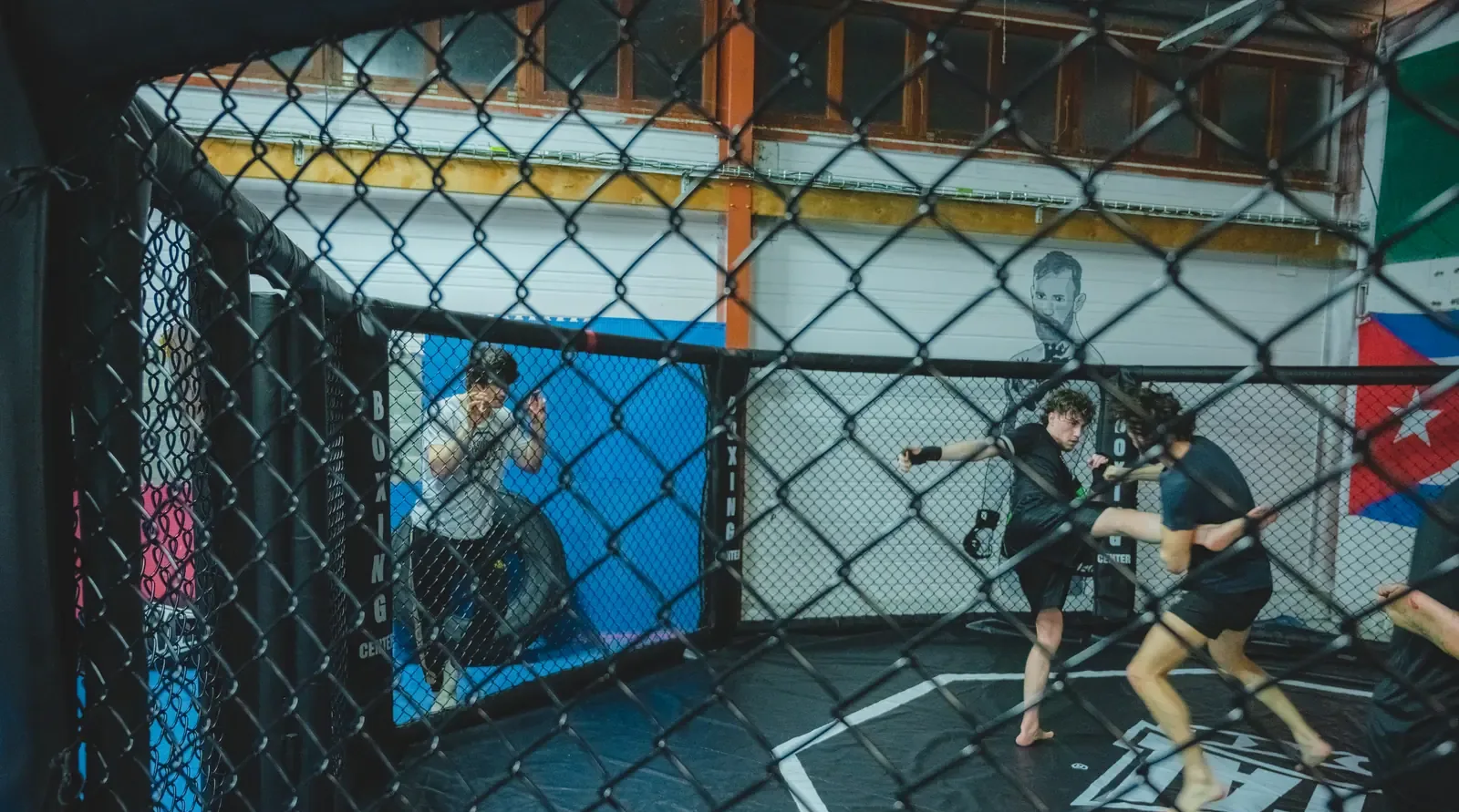Cours de MMA dans l’octogone de 7 mètres du Boxing Center Ramonville, sous la charpente du plateau couvert.
